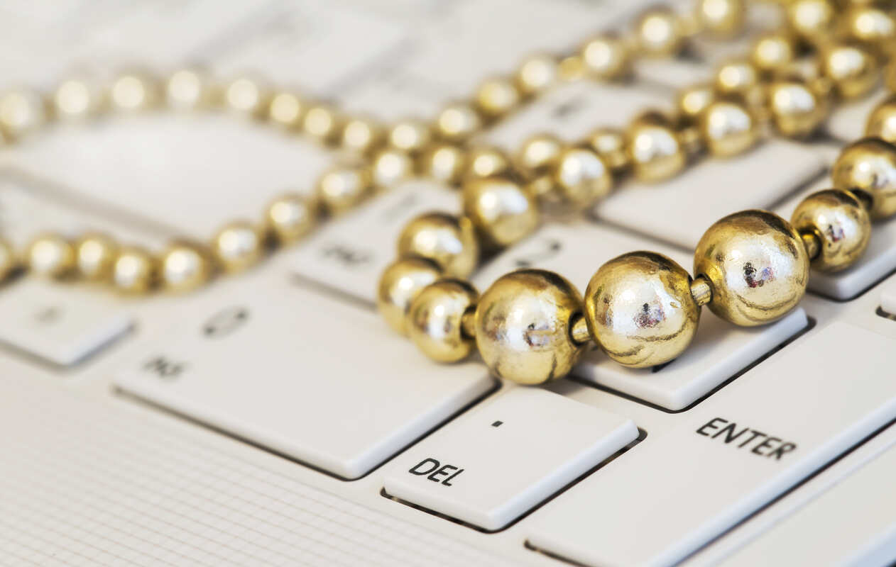 Gold beads draped on white keyboard