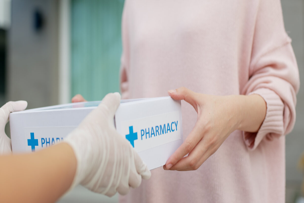 One person gives another a box of pharmaceutical products
